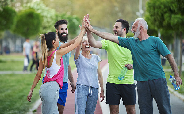 Laufgruppe, gemischtes Alter, macht High-Five.