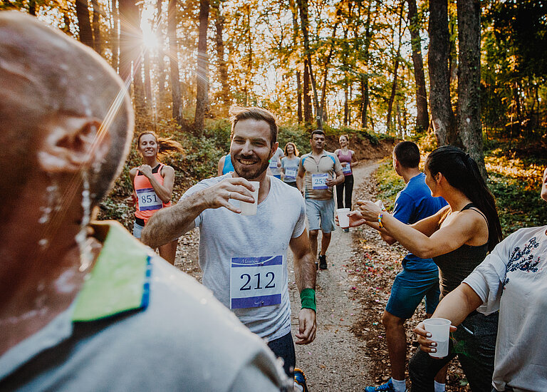 Läufer wird Wasser während des Marathons gereicht.