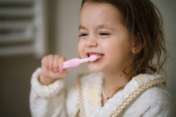 Ein kleines Mädchen putzt im Bad selbstständig Zähne.