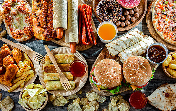 Bild von vielem, verschiedenem Fastfood wie Burger, Pizza, Hot Dogs, Donuts und weiteres.