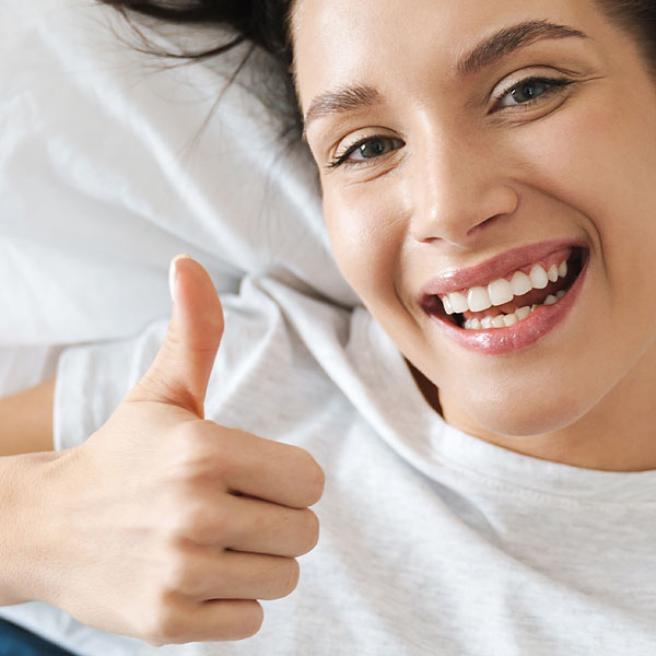 Lachende Frau zeigt Daumen nach oben.