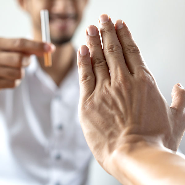 Person lehnt mit Handzeichen eine Zigarette ab