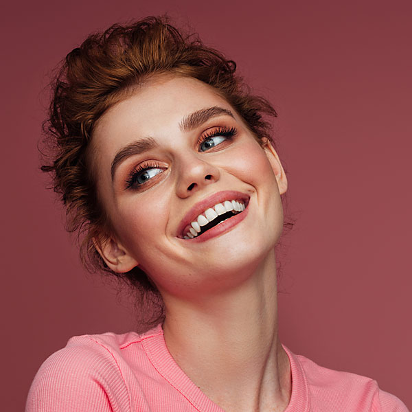 Portrait einer lachenden Frau mit zusammengesteckten Haaren.