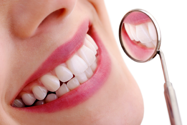 Ein schönes Lächeln einer Frau, mit einem Zahnarztspiegel vor dem Mund.