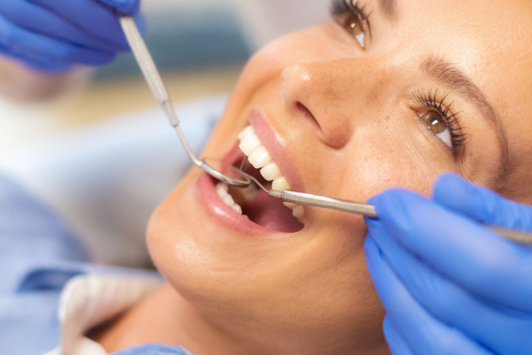 Eine Frau liegt auf dem Zahnarztstuhl und hat den Mund geöffnet zur Kontrolle