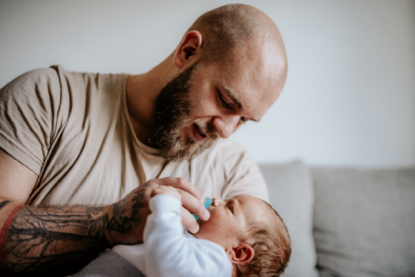 Ein Mann hält ein Baby in Arm und lächelt dabei.